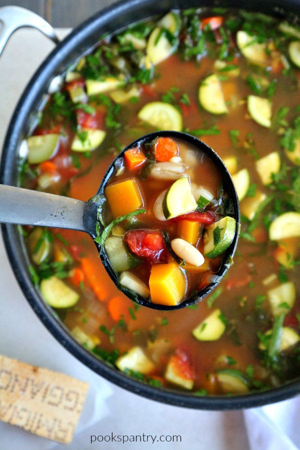 ladle of autumn minestrone soup over pot