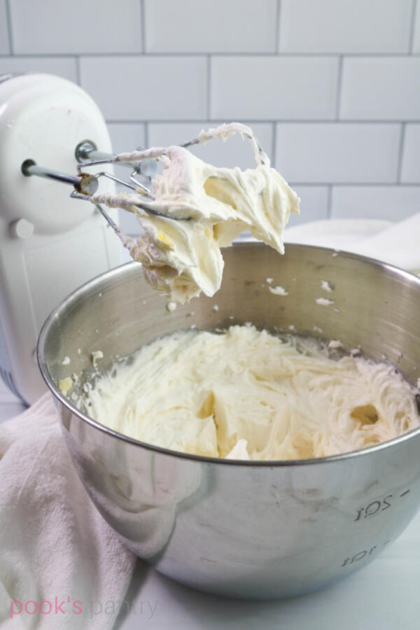 Lemon buttercream in mixing bowl with electric mixer.