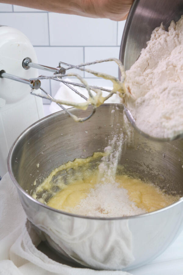 Adding flour to cupcake batter in mixing bowl.