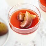 Panna cotta with poached figs in clear glasses on white background.
