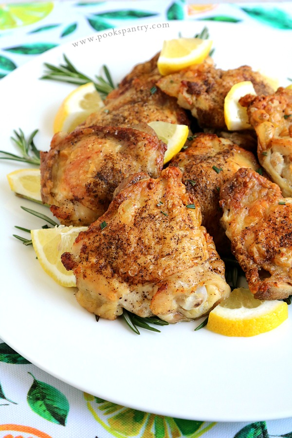 crispy rosemary lemon chicken thighs on platter with sprigs of rosemary and lemon
