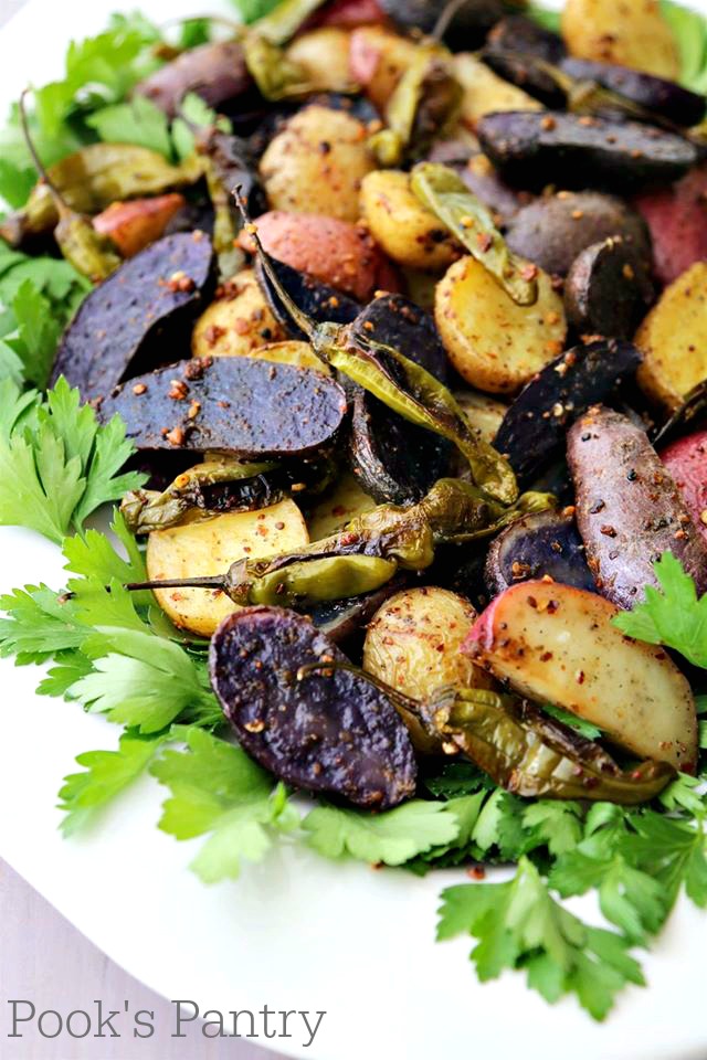 roasted fingerling potatoes with shishito peppers on white platter with herbs