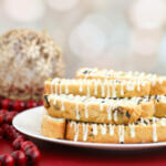 Cranberry pistachio biscotti on a white plate with a red surface underneath.
