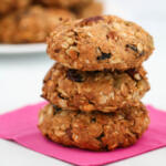 3 granola cookies stacked on top of each other, on top of a pink napkin.