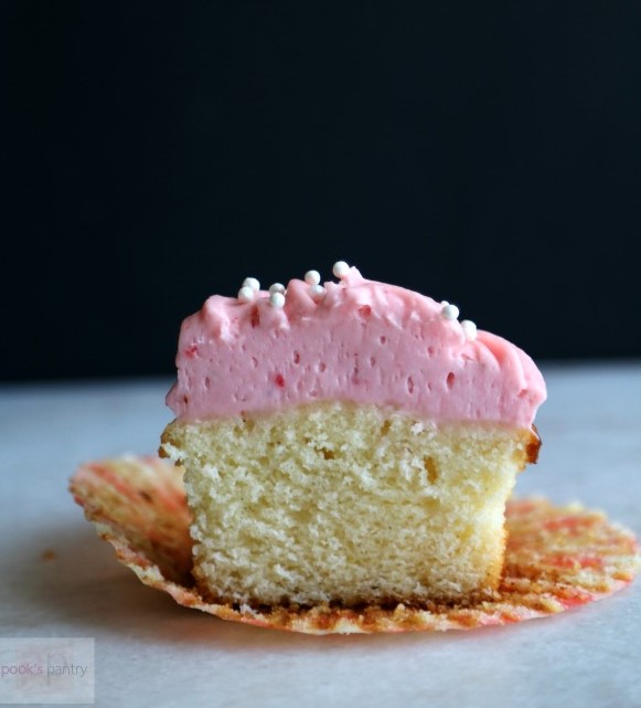 vanilla cupcakes with strawberry frosting cut in half