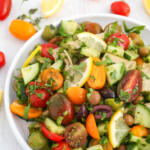 Mediterranean tomato cucumber salad on a white plate with a raised rim.