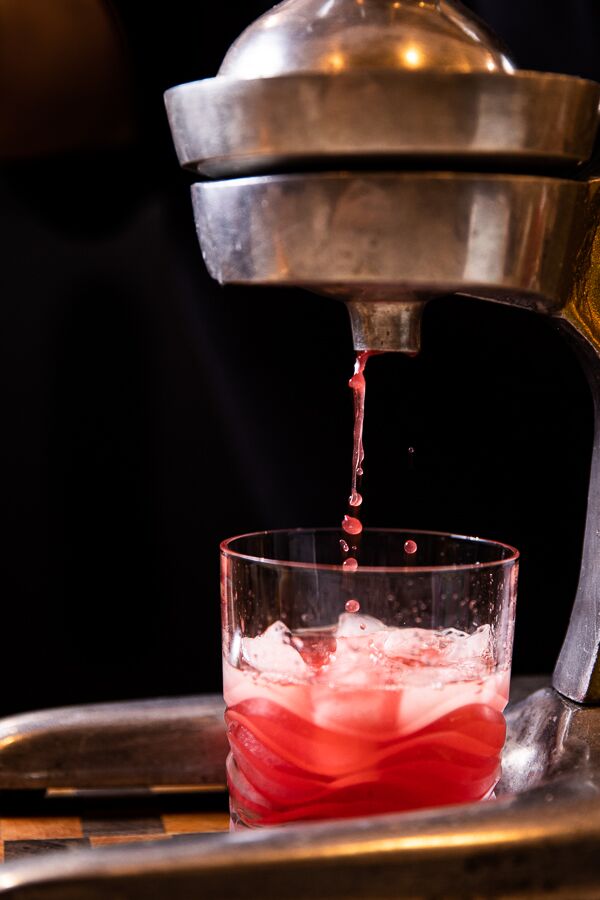 Blood orange being juiced into a glass.