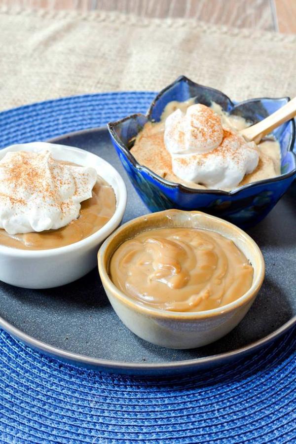 three bowls of butterscotch pudding on platter with blue placemat
