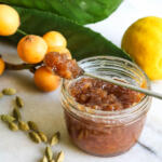Loquat cardamom jam on spoon with jam jar.