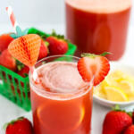 Strawberry lemonade iced tea with paper straw and sliced strawberry garnish.