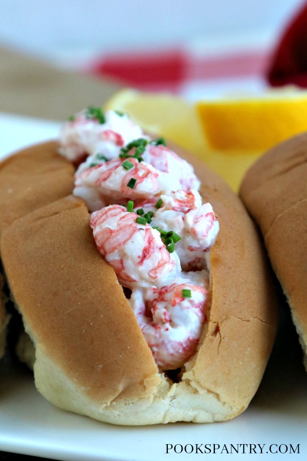 langostino lobster roll on white plate with chives