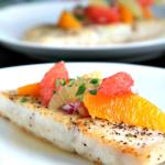 corvina with citrus on white plate with fish in background