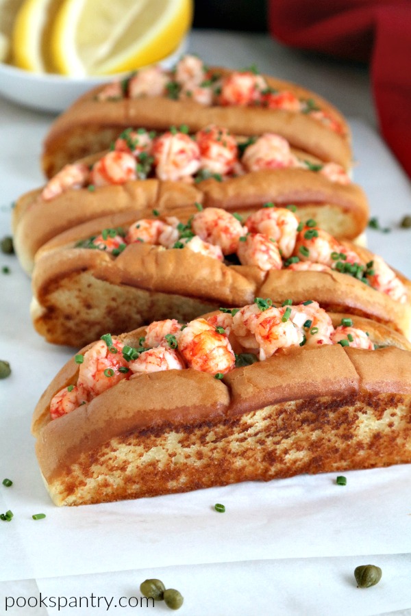 Langostino lobster roll recipe on parchment paper with capers.