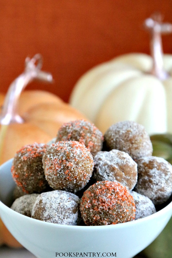 rum balls in white bowl with oragnge background and pumpkin decorations