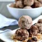 stacked chocolate coconut rum balls on white plate