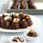 chocolate covered rum balls with white chocolate drizzle