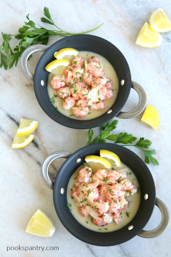 overhead view of garlic butter prawns in pans with lemon and parsley