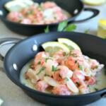 langostinos in garlic butter sauce in metal pan.