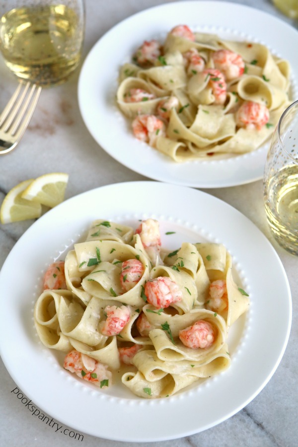 pappardelle with langostino on white plates with wine