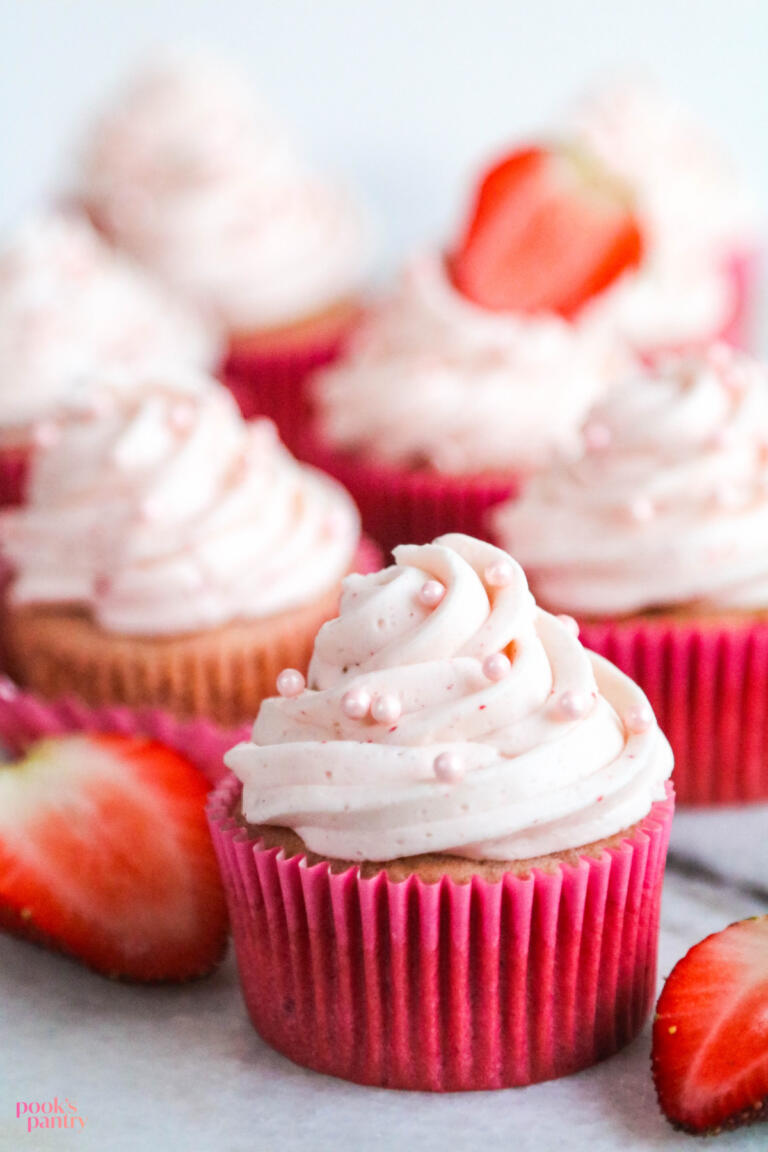 Frosted strawberry cream cheese cupcake on marble board.