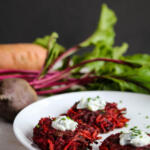 Sweet potato and beet fritters on white plate with beets in the background.
