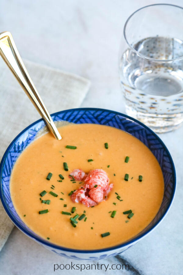 langostino bisque in blue and white bowl with gold spoon