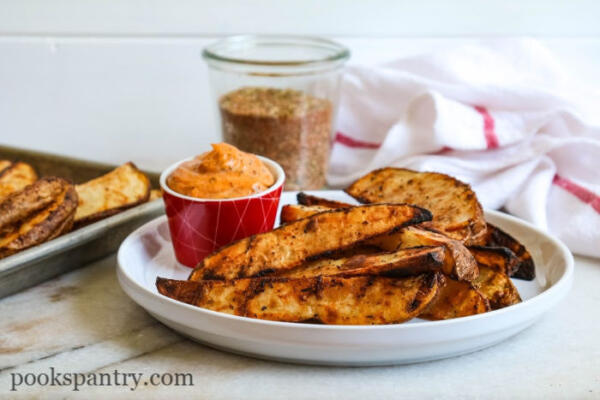 cajun grilled potato wedges on white plate with dipping sauce
