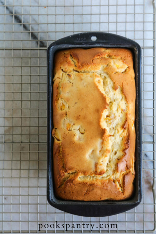 peaches and cream cake in loaf pan on cooling rack
