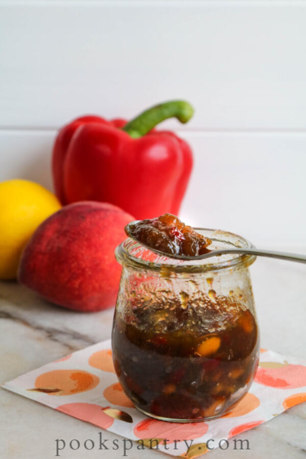 peach pepper jam with peach, pepper and lemon in background