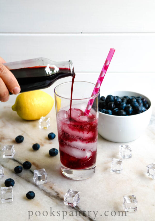 pouring blueberry syrup for drinks into glass