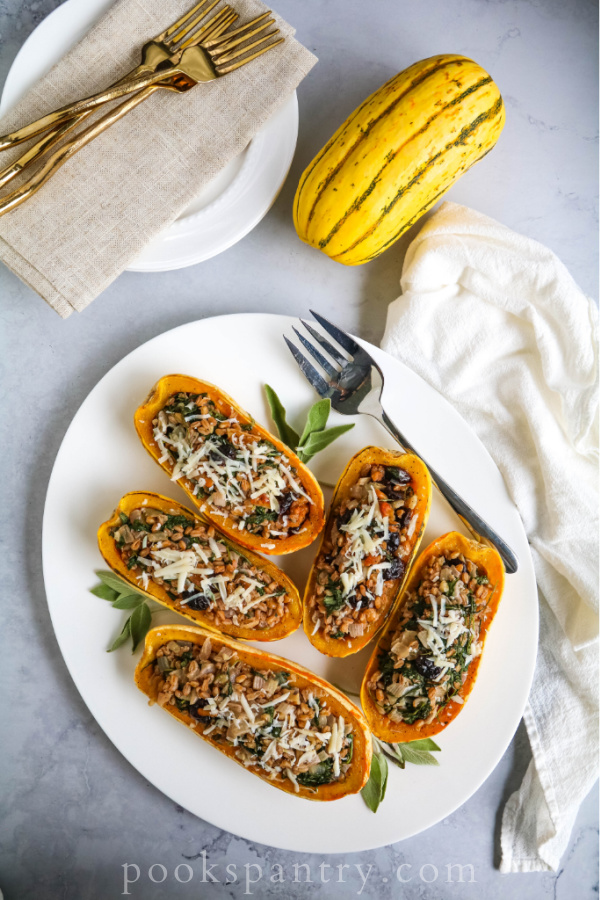 Stuffed squash with farro on platter with sage leaves.