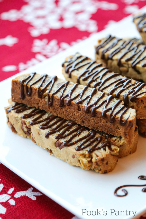 stacked butter pecan biscotti on white plate with red tablecloth