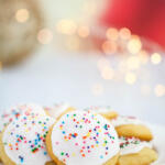 Lemon ricotta cookies on a white plate with Christmas lights in the background.