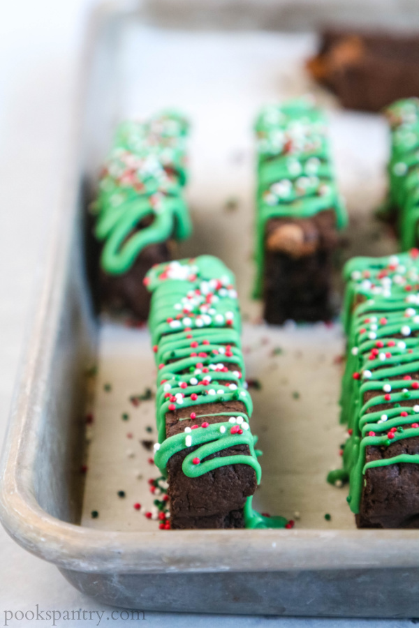 close up of chocolate mint biscotti with green drizzle and sprinkles on sheet pan