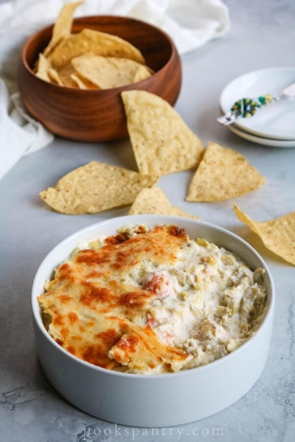artichoke langostino dip in white bowl with chips