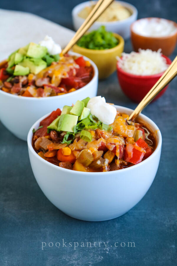 veggie chili with sour cream and avocado in white bowls