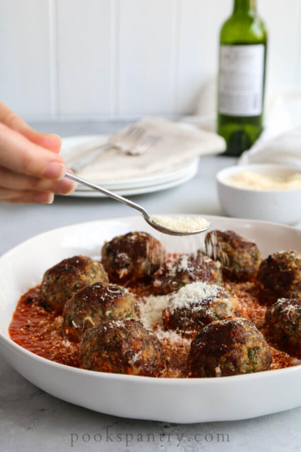 sprinkling cheese on meatballs