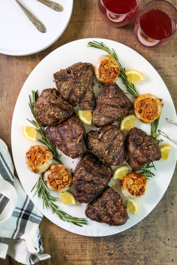 Grilled lamb chops with garlic, lemon and rosemary on white platter with towel