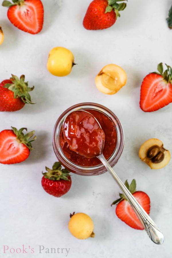 overhead shot of strawberry loquat jam jar with jam on spoon