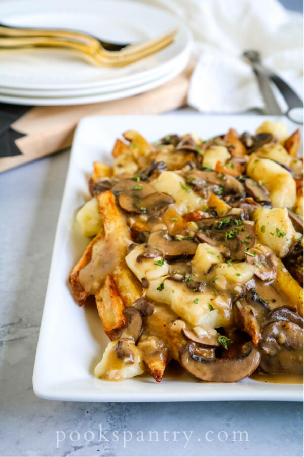Vegetarian poutine on a white platter with mushroom gravy is one of the more decadent vegetarian recipes for dinner.