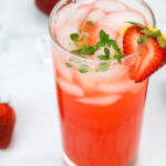 Strawberry thyme lemonade in tall clear glass with fresh strawberry garnish.