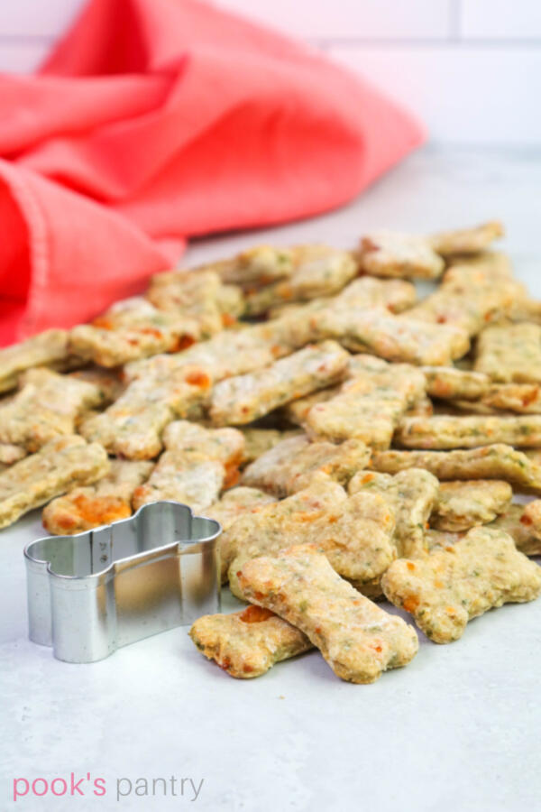 DIY dog biscuits with cheese and apples in a big pile with coral colored napkin in background.