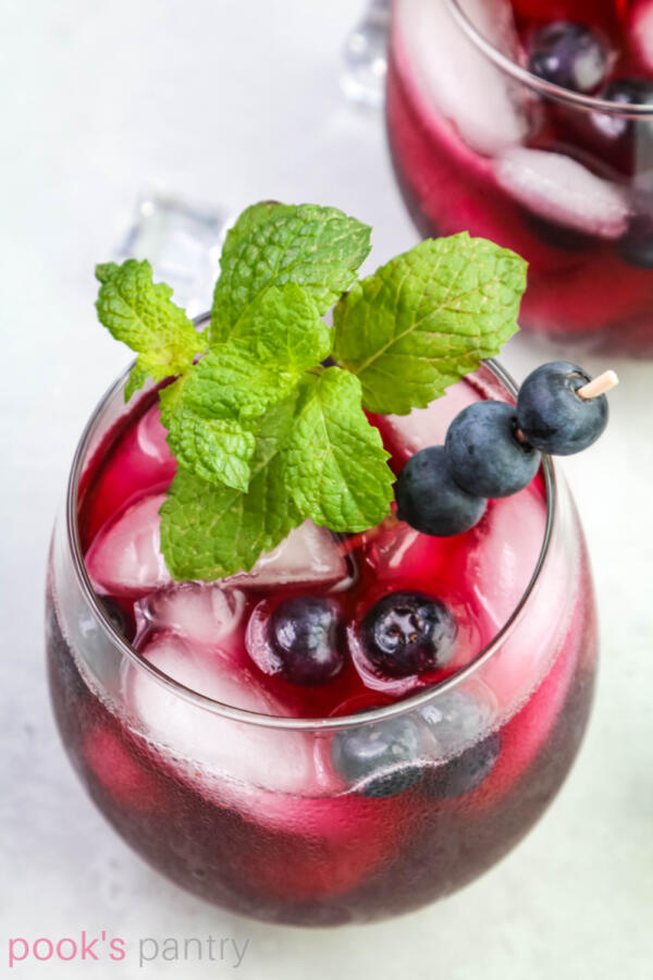 Overhead photo of blueberry lemonade in round glass with mint garnish.