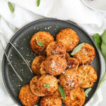 Butternut squash risotto cakes on a black plate.
