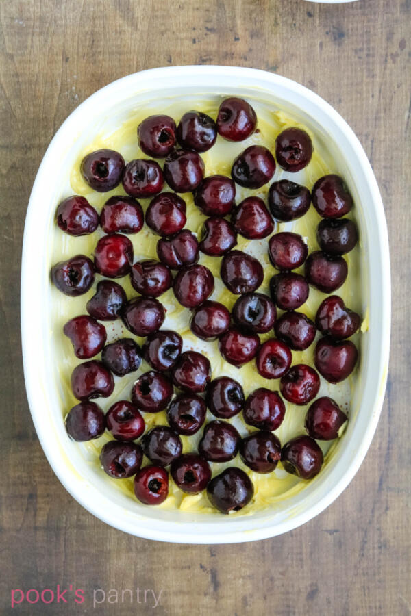 Fresh sweet cherries in buttered shallow baking dish.