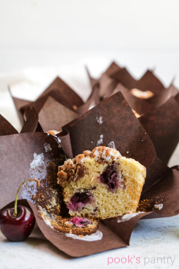 Muffin cut in half with fresh cherries inside and streusel on top.