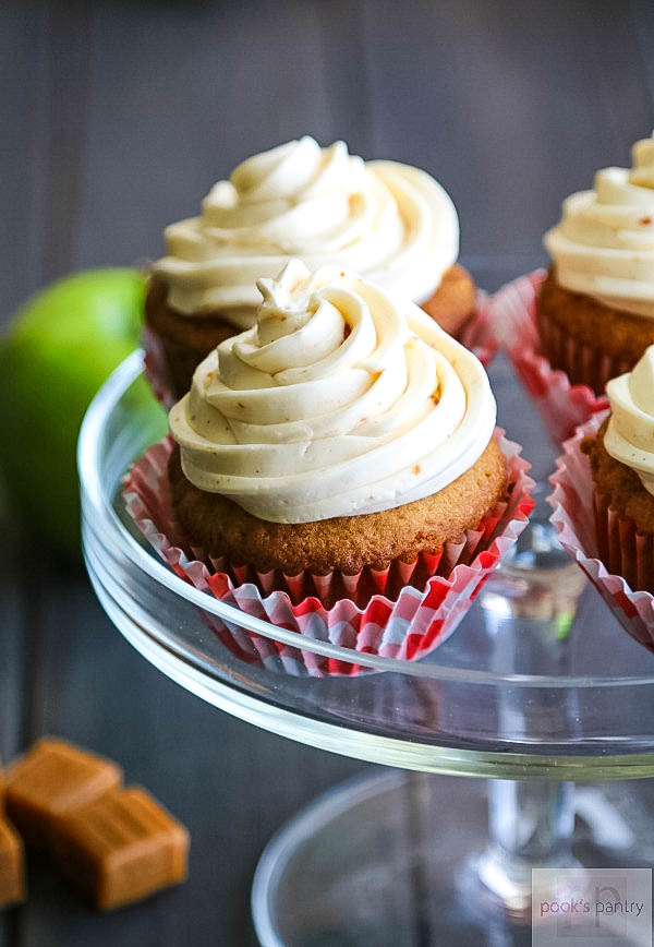 Caramel apple cupcakes on clear glass dessert stand.