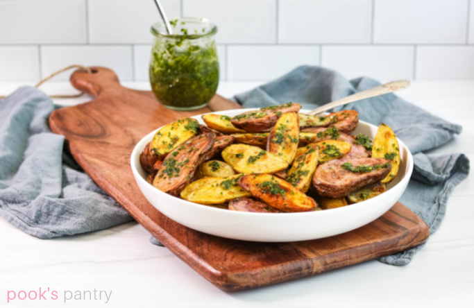 Roast potatoes with gremolata sauce in white bowl.