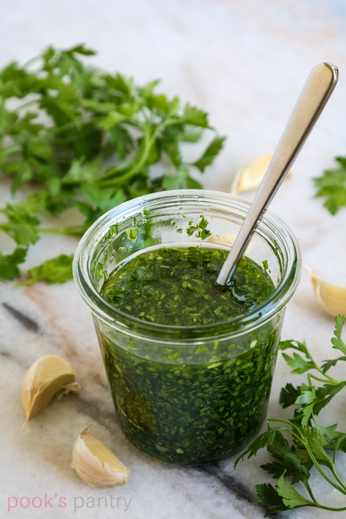 Gremolata sauce in glass jar with a spoon.