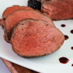 Sliced beef tenderloin for Thanksgiving with blackberry gastrique showing the pink inside of roast.